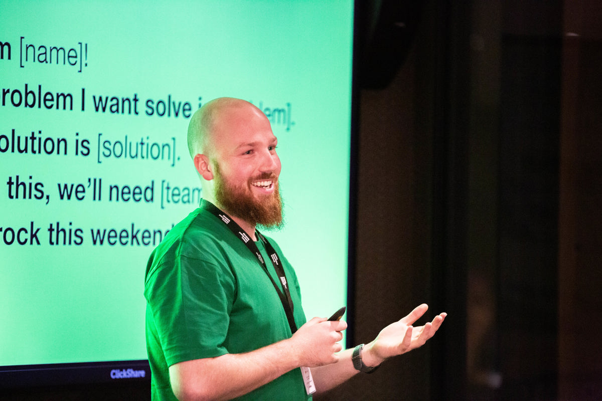A presenter in a green T-shirt presents to an audience